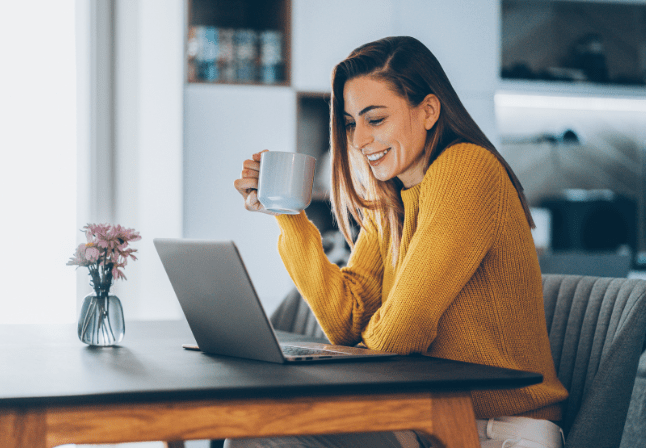 femme pull jaune prend un café devant son ordinateur