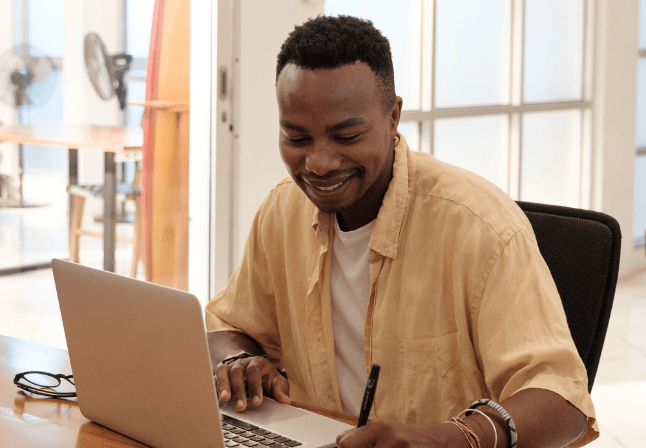 homme chemise jaune derrière ordinateur en train de travailler
